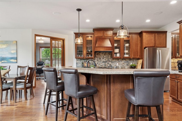 11200 Walnut Ln, Woodbury, MN 55129 - kitchen with brown cabinetry, decorative backsplash, wood finished floors, a kitchen bar, and light stone counters