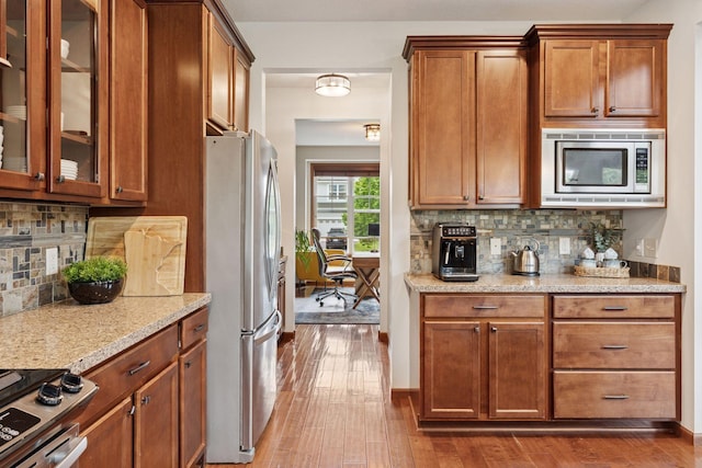 11200 Walnut Ln, Woodbury, MN 55129 - kitchen with appliances with stainless steel finishes, dark wood-style flooring, light stone counters, and glass insert cabinets