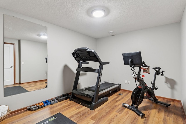 11200 Walnut Ln, Woodbury, MN 55129 - exercise room featuring wood finished floors, baseboards, and a textured ceiling