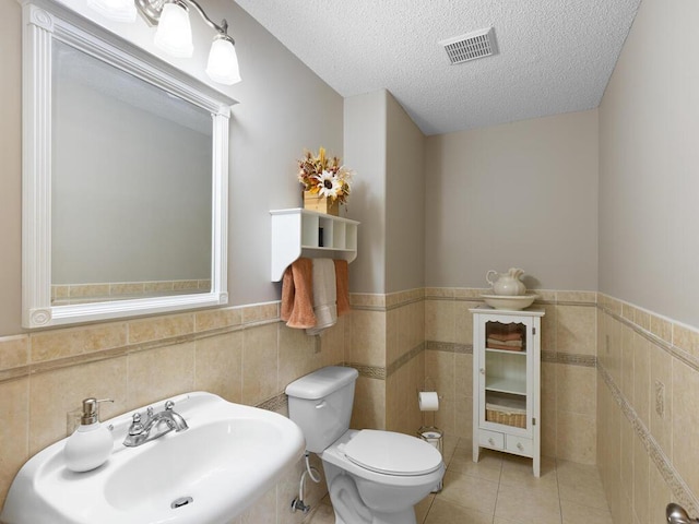 6700 210th Lane Cir N, Forest Lake, MN 55025 - bathroom with tile walls, a textured ceiling, tile patterned floors, and wainscoting