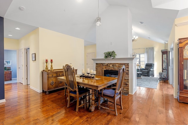 24064 Rivers Edge Rd, Rogers, MN 55374 - dining area with lofted ceiling, wood-type flooring, a stone fireplace, recessed lighting, and a chandelier