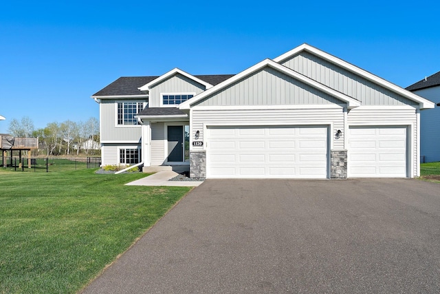 1120 7th Ave NE, Isanti, MN 55040 - view of front of house featuring asphalt driveway, a garage, stone siding, and a shingled roof