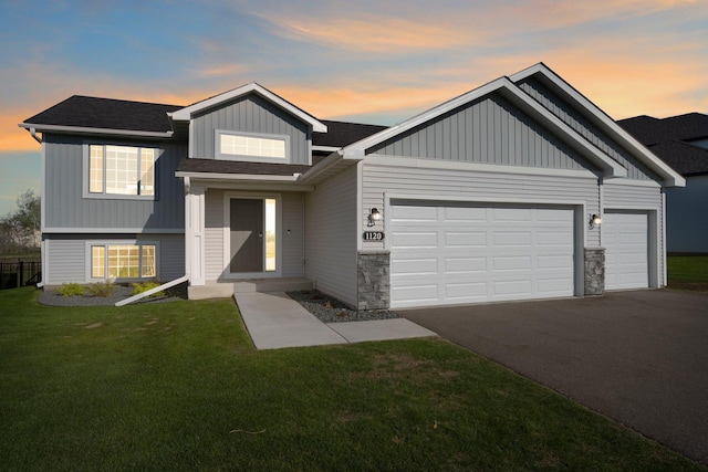 1120 7th Ave NE, Isanti, MN 55040 - view of front facade featuring an attached garage, driveway, a front lawn, board and batten siding, and a shingled roof
