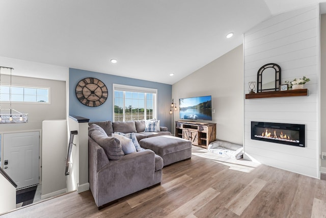 1120 7th Ave NE, Isanti, MN 55040 - living room with lofted ceiling, wood finished floors, a chandelier, a fireplace, and healthy amount of natural light