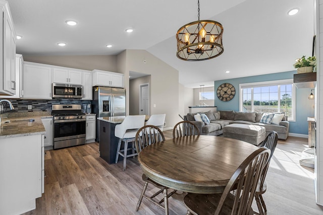 1120 7th Ave NE, Isanti, MN 55040 - dining area featuring vaulted ceiling, healthy amount of natural light, wood finished floors, a chandelier, and recessed lighting