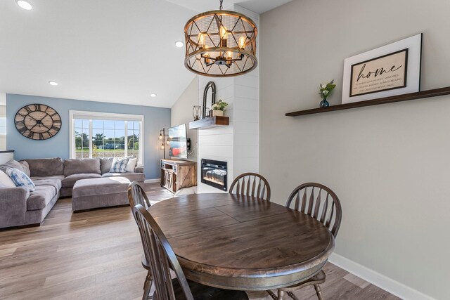1120 7th Ave NE, Isanti, MN 55040 - dining space with lofted ceiling, light wood-style floors, a glass covered fireplace, a chandelier, and recessed lighting