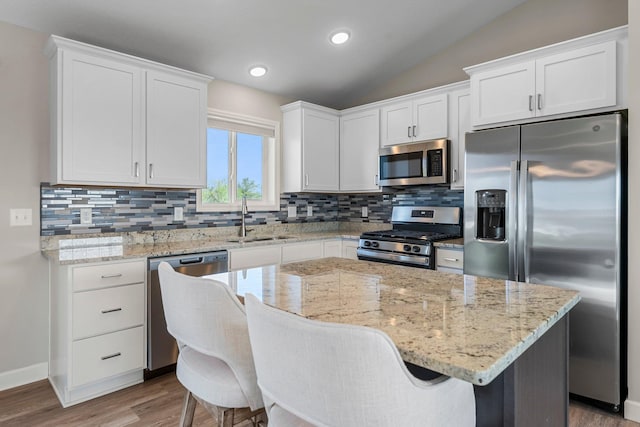 1120 7th Ave NE, Isanti, MN 55040 - kitchen featuring stainless steel appliances, tasteful backsplash, white cabinetry, wood finished floors, and lofted ceiling
