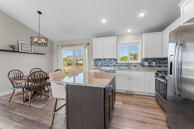 1120 7th Ave NE, Isanti, MN 55040 - kitchen with appliances with stainless steel finishes, tasteful backsplash, white cabinets, plenty of natural light, and vaulted ceiling