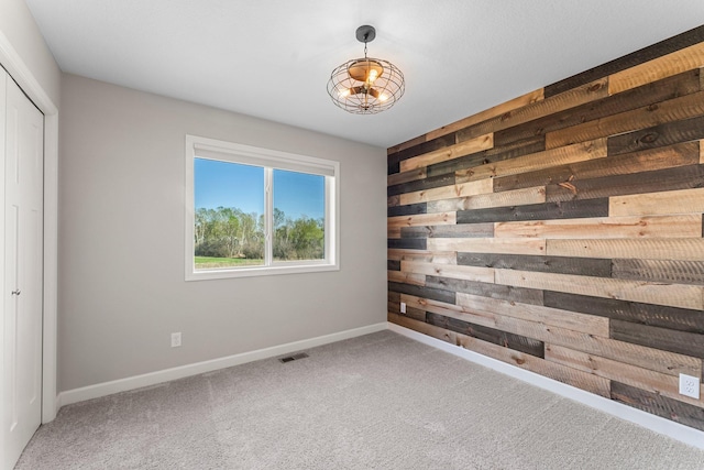 1120 7th Ave NE, Isanti, MN 55040 - empty room featuring wood walls, carpet, and a chandelier