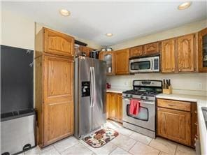 1555 Bluebird Ln, Mound, MN 55364 - kitchen with appliances with stainless steel finishes, brown cabinets, glass insert cabinets, light countertops, and recessed lighting