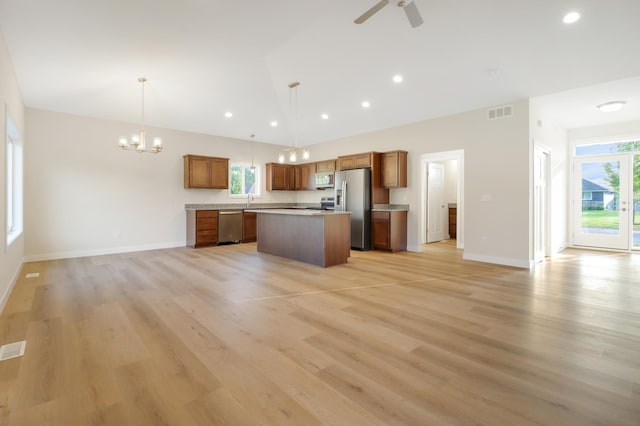 31079 Magnolia Ridge Way, Lindstrom, MN 55045 - kitchen with stainless steel appliances, open floor plan, a center island, brown cabinets, and vaulted ceiling