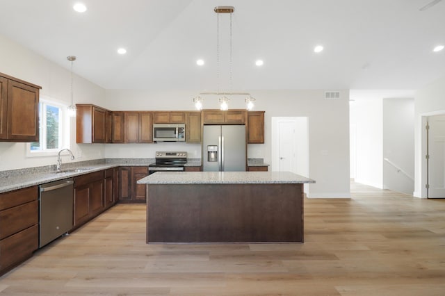 31079 Magnolia Ridge Way, Lindstrom, MN 55045 - kitchen with stainless steel appliances, a sink, a kitchen island, light wood-style flooring, and light stone countertops