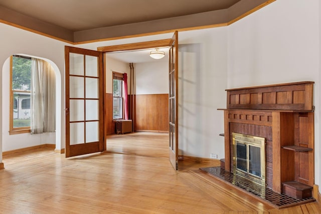 518 32nd St, Minneapolis, MN 55408 - unfurnished living room with radiator heating unit, light wood-type flooring, french doors, and a brick fireplace