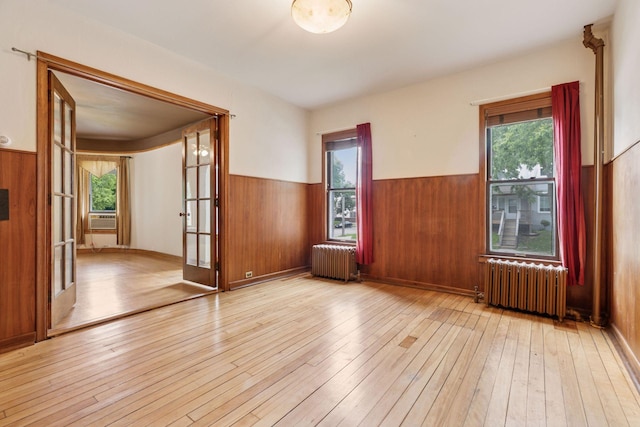 518 32nd St, Minneapolis, MN 55408 - unfurnished room featuring radiator heating unit, a wainscoted wall, hardwood / wood-style flooring, wooden walls, and french doors