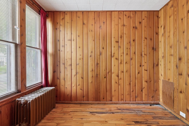 518 32nd St, Minneapolis, MN 55408 - empty room featuring radiator, light wood-style floors, and wooden walls