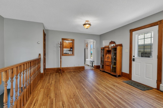 entryway featuring light wood-style flooring, baseboards, and a textured ceiling