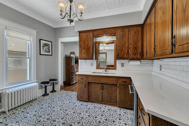 kitchen featuring radiator heating unit, a sink, light countertops, tasteful backsplash, and a chandelier