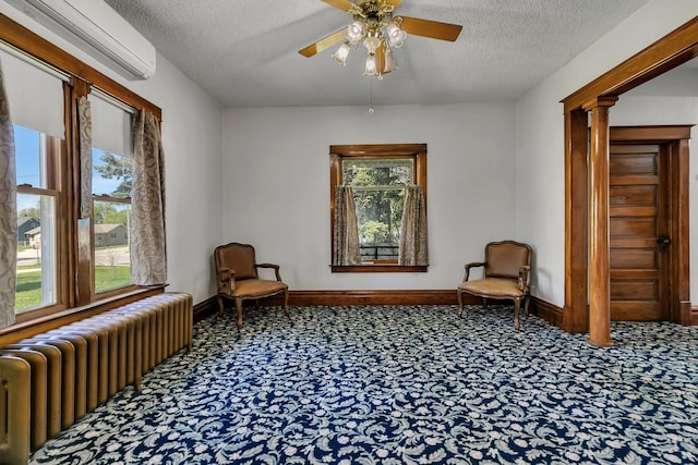 living area with radiator heating unit, carpet floors, an AC wall unit, a textured ceiling, and ceiling fan