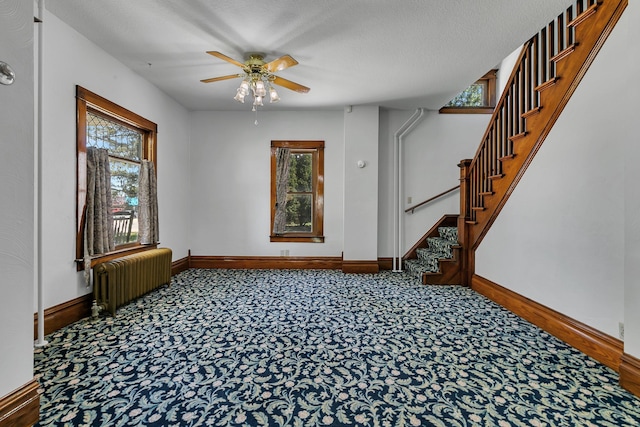 spare room with radiator, baseboards, plenty of natural light, stairs, and a textured ceiling