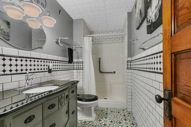 full bathroom with tile walls, toilet, a stall shower, tile patterned floors, and vanity