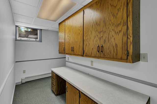 unfurnished office featuring baseboard heating, carpet flooring, baseboards, and a drop ceiling