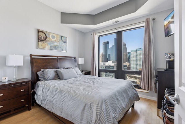 500 Grant St Unit 2509, Minneapolis, MN 55404 - bedroom featuring light wood-type flooring, a skyline view, and baseboards