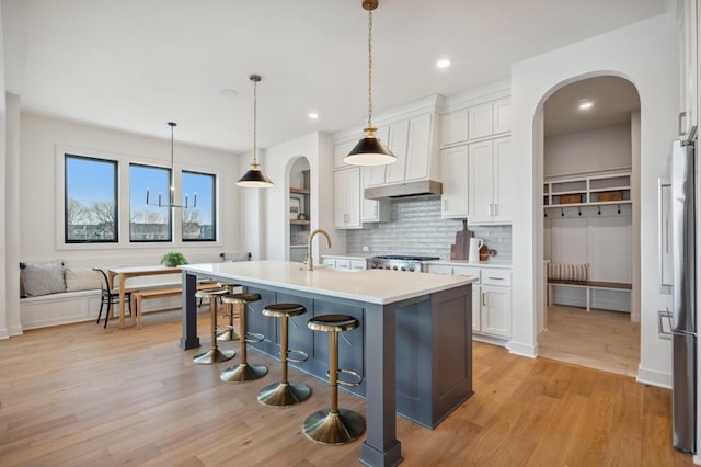 10382 Peony Ln N, Maple Grove, MN 55311 - kitchen featuring high end refrigerator, backsplash, white cabinets, light countertops, and arched walkways