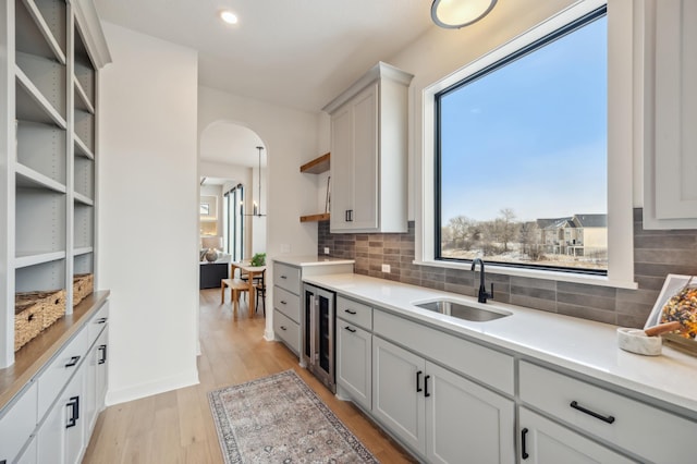 10382 Peony Ln N, Maple Grove, MN 55311 - kitchen featuring a sink, beverage cooler, open shelves, backsplash, and arched walkways