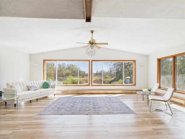 living area with ceiling fan, light wood-type flooring, and a textured ceiling