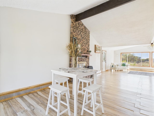 dining area featuring wood finished floors, a brick fireplace, and baseboards