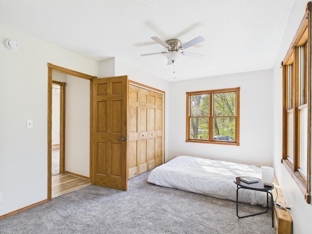 carpeted bedroom with a closet, baseboards, and a ceiling fan