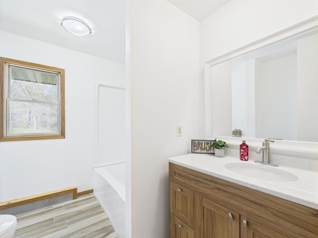 bathroom with vanity, toilet, wood finished floors, and a tub to relax in