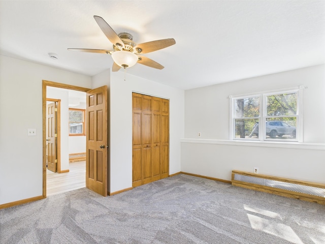 unfurnished bedroom featuring carpet floors, a closet, baseboards, and ceiling fan