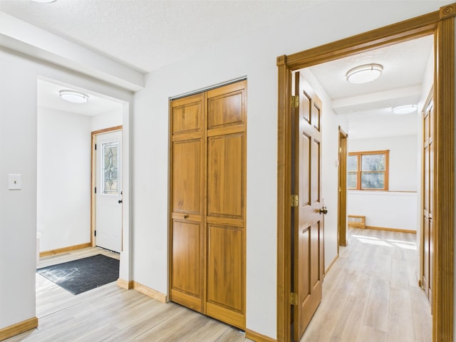 hallway with light wood-type flooring and baseboards