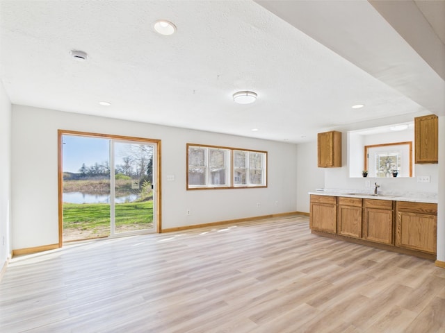 unfurnished living room featuring baseboards, healthy amount of natural light, light wood-style floors, and recessed lighting