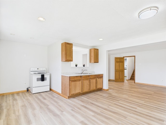 kitchen with electric range, a sink, light wood-type flooring, light countertops, and recessed lighting