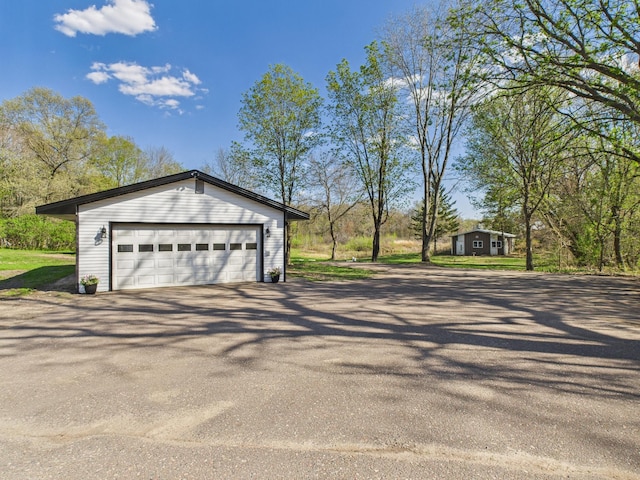 view of side of home with an outdoor structure and asphalt driveway