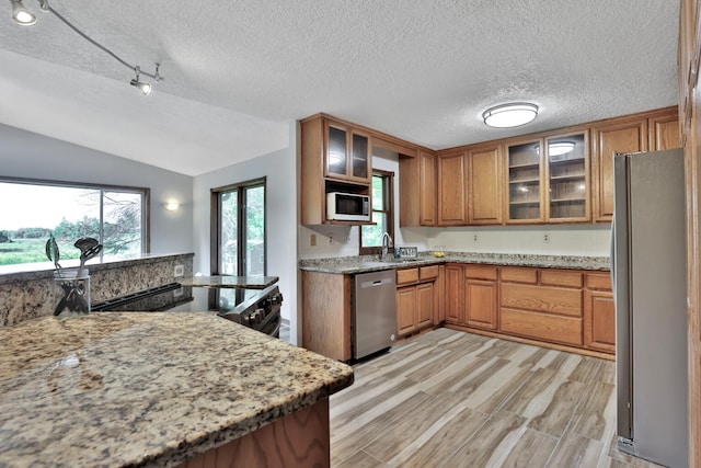 30145 Fir Trl, Stacy, MN 55079 - kitchen with stainless steel appliances, brown cabinets, a textured ceiling, vaulted ceiling, and light wood-style flooring