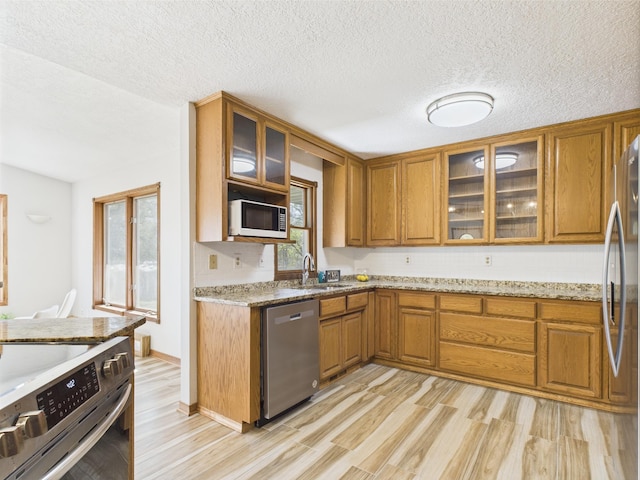 30145 Fir Trl, Stacy, MN 55079 - kitchen featuring stainless steel appliances, brown cabinets, light wood-type flooring, light stone countertops, and a textured ceiling