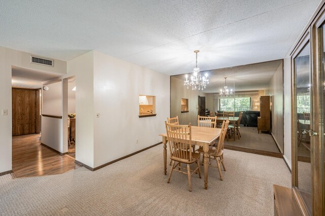 2465 Londin Ln E Unit 212, Maplewood, MN 55119 - dining room featuring light carpet, a chandelier, baseboards, and a textured ceiling