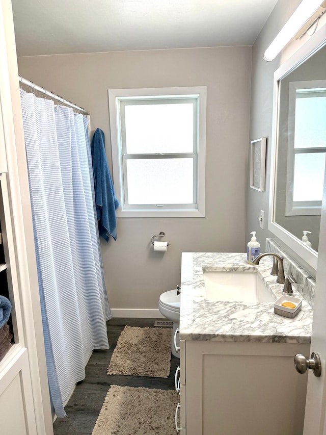bathroom with vanity, wood finished floors, baseboards, toilet, and curtained shower