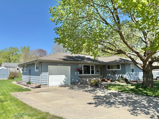ranch-style home featuring a garage, concrete driveway, a front lawn, a shed, and an outdoor structure