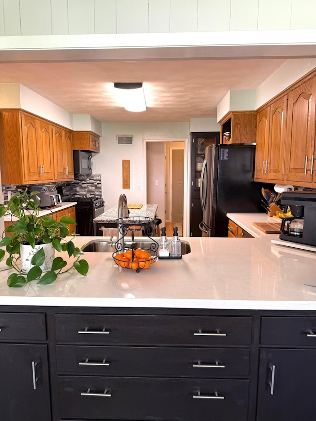 kitchen with light countertops, brown cabinets, range with gas stovetop, and tasteful backsplash