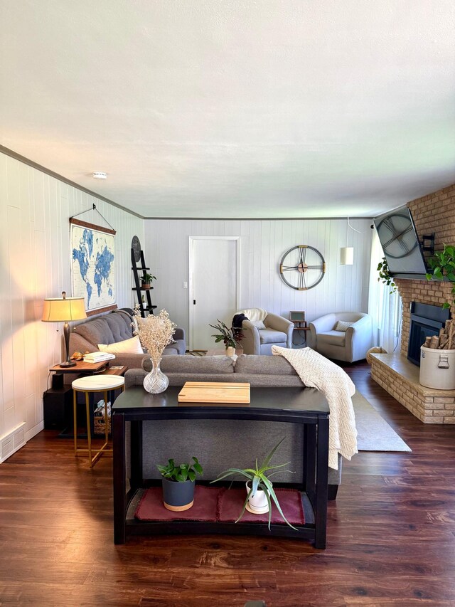 living room with a brick fireplace and wood finished floors