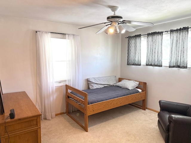 bedroom with light carpet, a ceiling fan, and baseboards