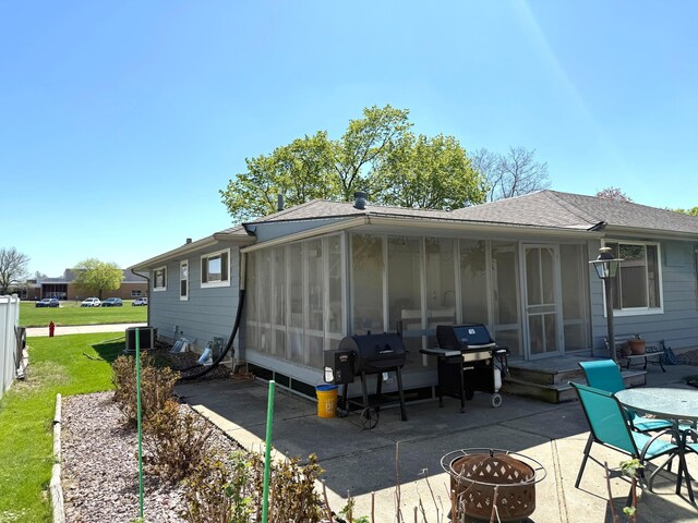 rear view of property with an outdoor fire pit, a sunroom, a patio area, a shingled roof, and central air condition unit