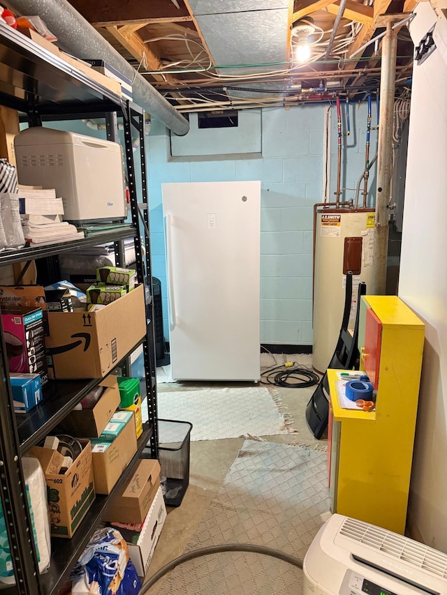unfinished below grade area featuring electric water heater, concrete block wall, and freestanding refrigerator