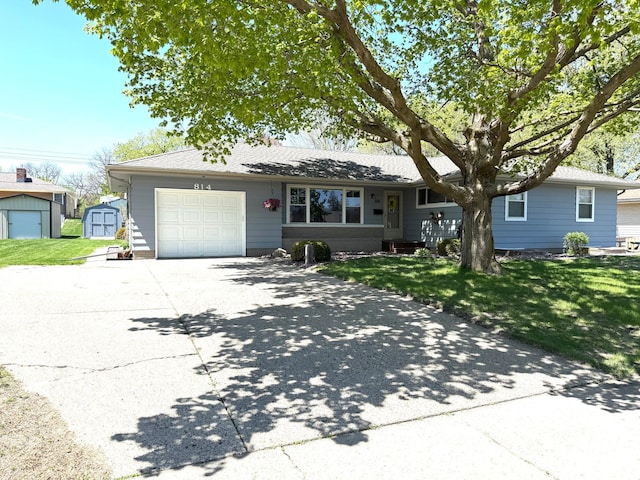 single story home featuring a storage shed, an attached garage, a front yard, concrete driveway, and an outdoor structure