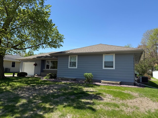 view of front of home with central AC, a garage, and a front yard