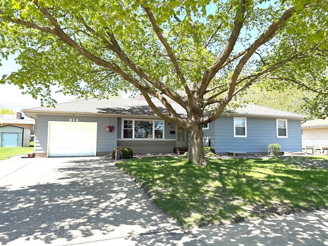 ranch-style home featuring driveway, an attached garage, and a front lawn